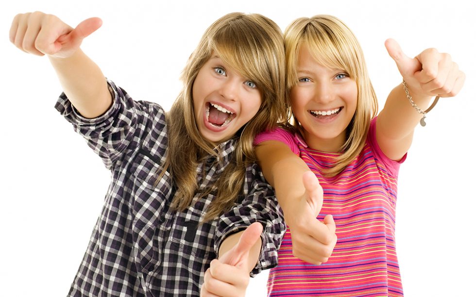 Portrait of happy teen girls showing thumbs up isolated one white